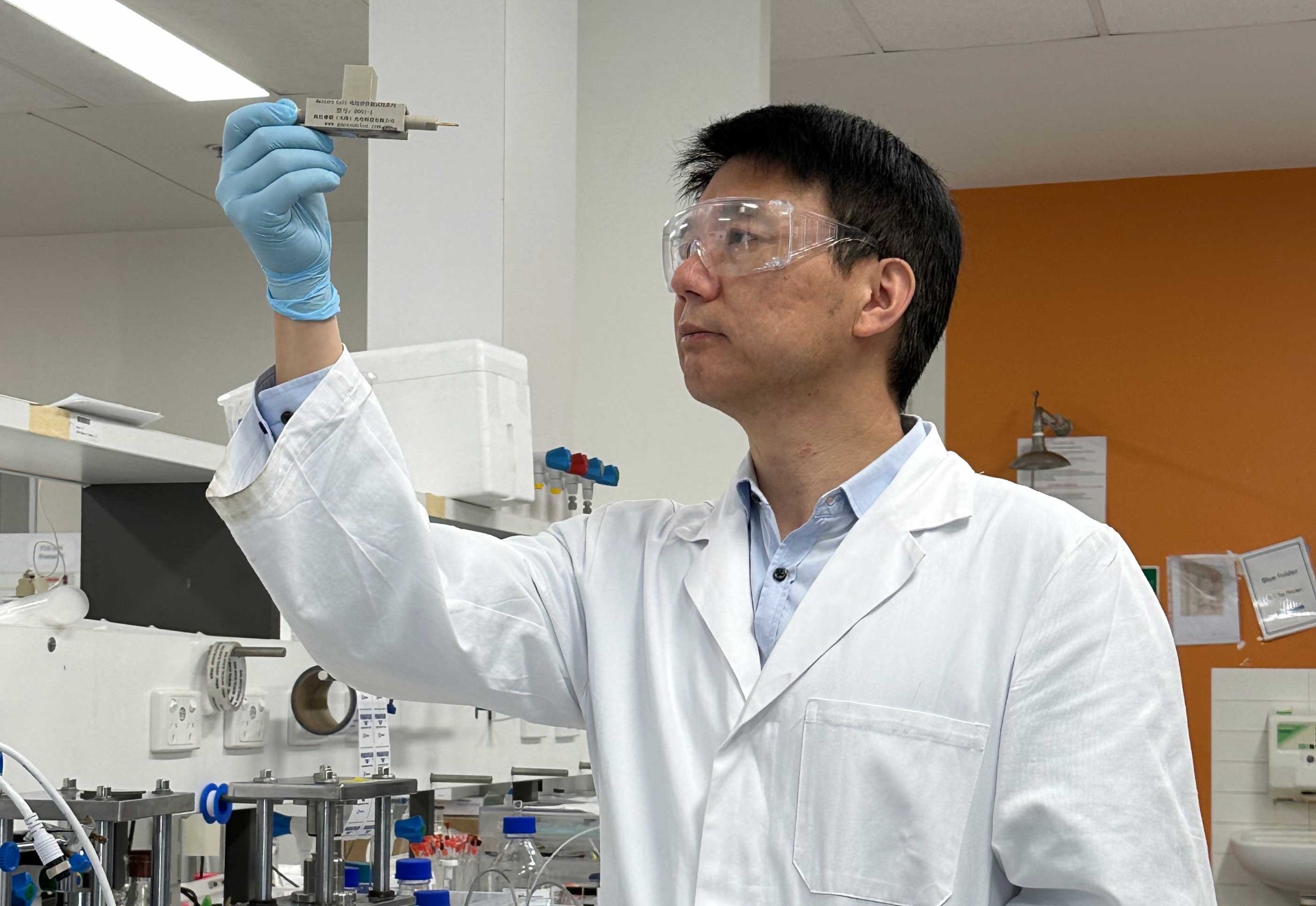 Professor Chuan Zhao holds up a prototype of a proton battery in the lab