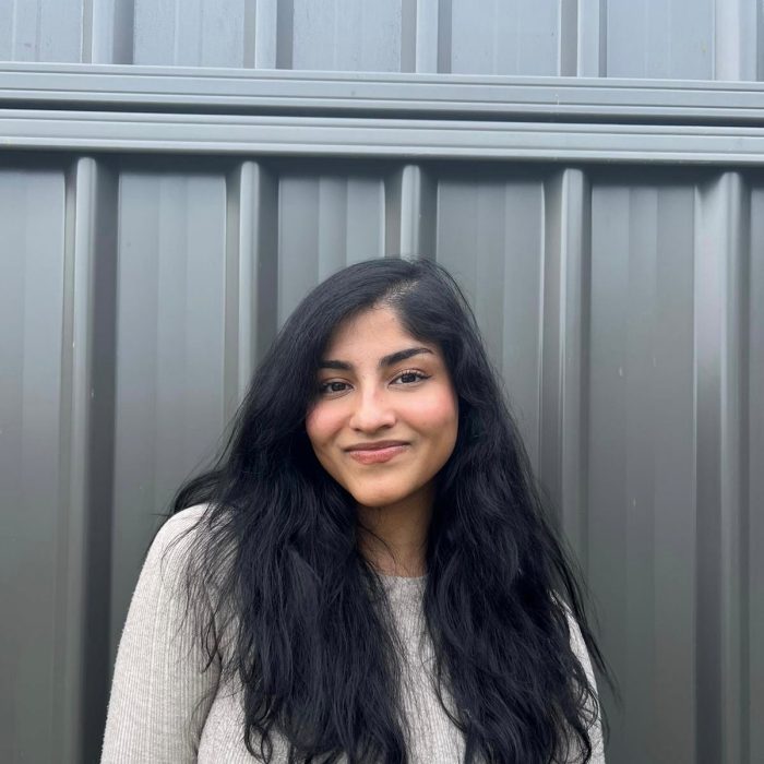 A picture of a girl standing in front of a grey wall.