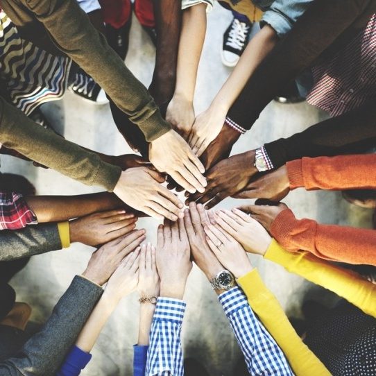 A group of different people putting their hands together