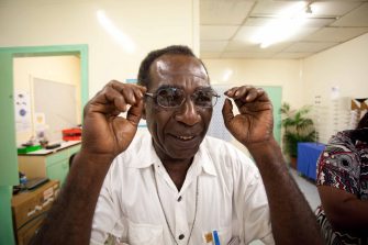 Older gentleman trying on glasses in an office