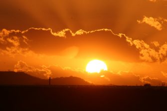 Orange sunset over flat horizon with clouds