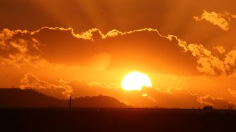 Orange sunset over flat horizon with clouds