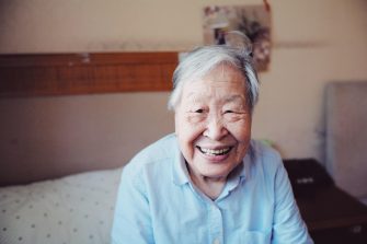 Elderly person in blue shirt smiling at camera
