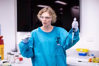 Lady in blue labcoat holding syringe