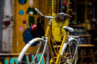 White and yellow bicycle with helmut hanging off handlebars