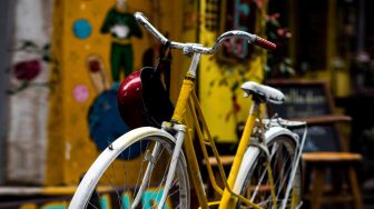White and yellow bicycle with helmut hanging off handlebars