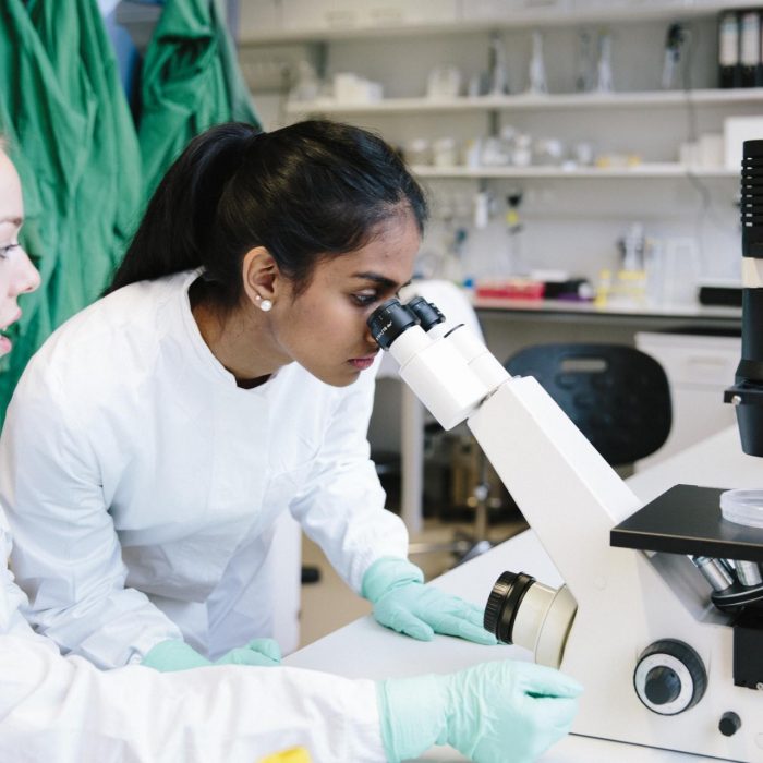 Scientist looking down microscope