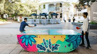 Students playing table tennis outdoors on campus