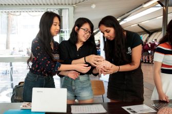 Three female students looking at a model of a brain