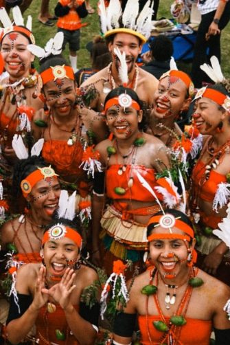 A woman in Indigenous dress stands in front of a see-through marquee shaped like a dome.