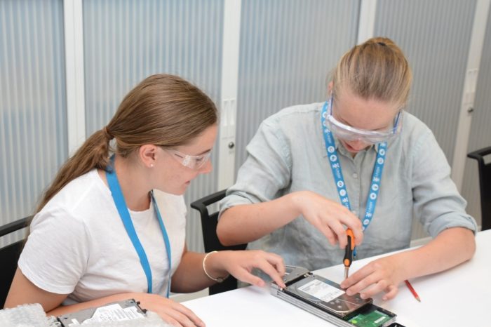 two students using screwdriver on machine