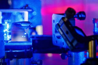 Blue laser on optical table in a quantum optics lab.
