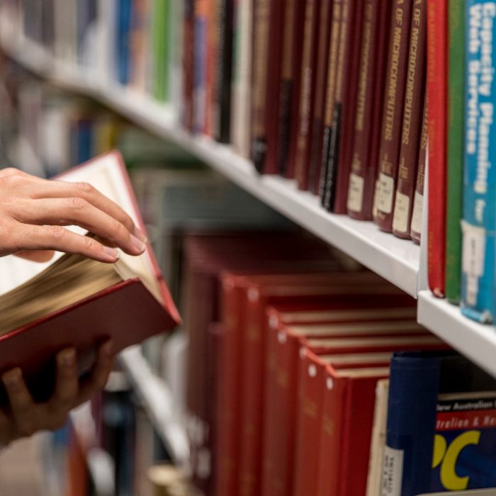 Student opening books in library