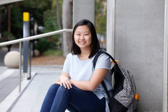 Female student sitting on steps with backpack