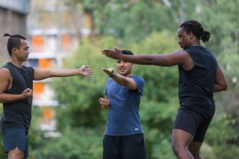 Male students warming up and stretching in park