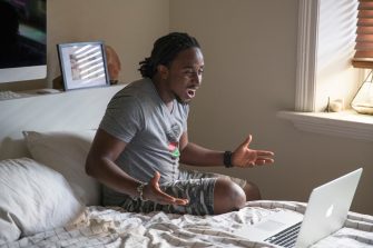 International Students at home on bed with laptop