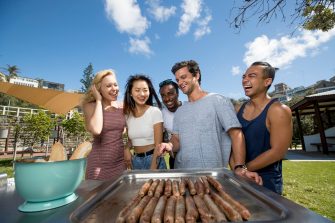Students having BBQ at the beach cooking sausages