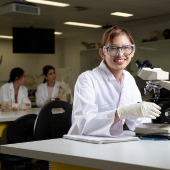Students in Science Lab with white coat, goggles and  microscopes