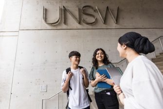 Students talking on L5 steps with UNSW logo behind them