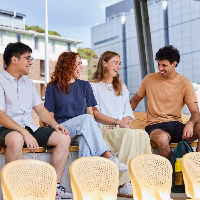 Four students sitting and laughing