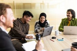 Light pink image of a megaphone with the words 8 March coming out  Support for significant days and eventsadd 4 people of mixed age and race in a meeting rooms with laptops working together