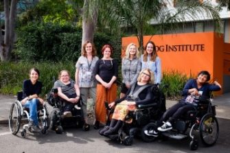 A group of 8 women stand outside the Black Dog Institute building. They are all smiling.
