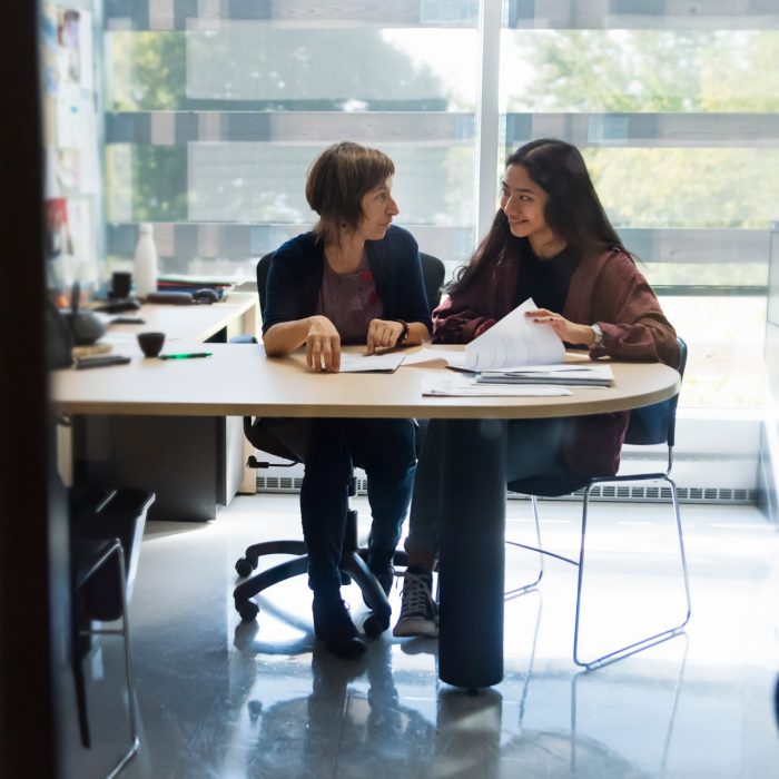 Counselling appointment for young asian woman student in counsellor College office. Horizontal indoors backlit full length shot with copy space.