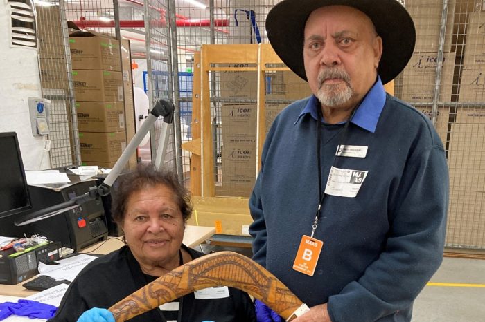 Aunty Marjie Dixon and Uncle Greg Simms holding a boomerang made by their father Robert Simms in La Perouse that commemorates the Sydney Harbour Bridge