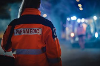 Female paramedic looking towards ambulance at night