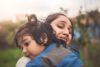 A Sad Indian Daughter Hugging Mother Outdoors. Mom with Her Kid, Little Girl with Frustrated Face Embracing Young Woman Outside.