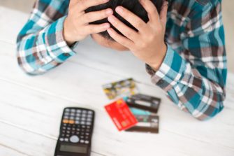 A woman worries with her head in her hands while looking at debit cards