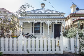 Corrugated iron house in Melbourne with a white fence in front of it