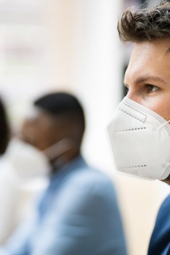 Three young people each wearing a face mask in the office