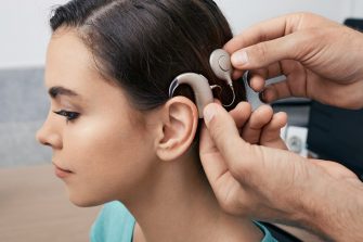 A woman has part of the cochlear implant technolgy attached behind her ear