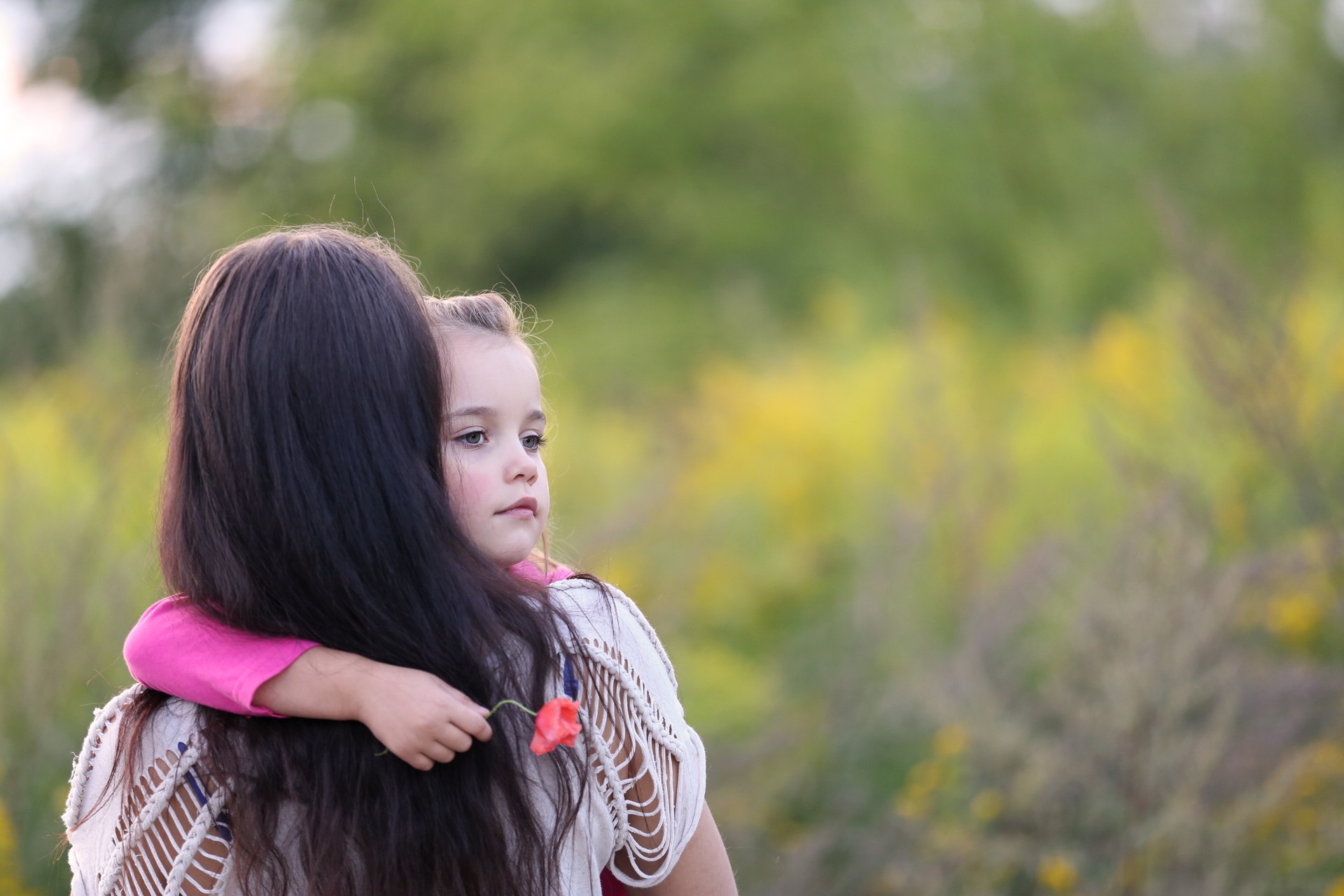 very sad little girl in her mother's arms outside, shallow depth of field, room for text