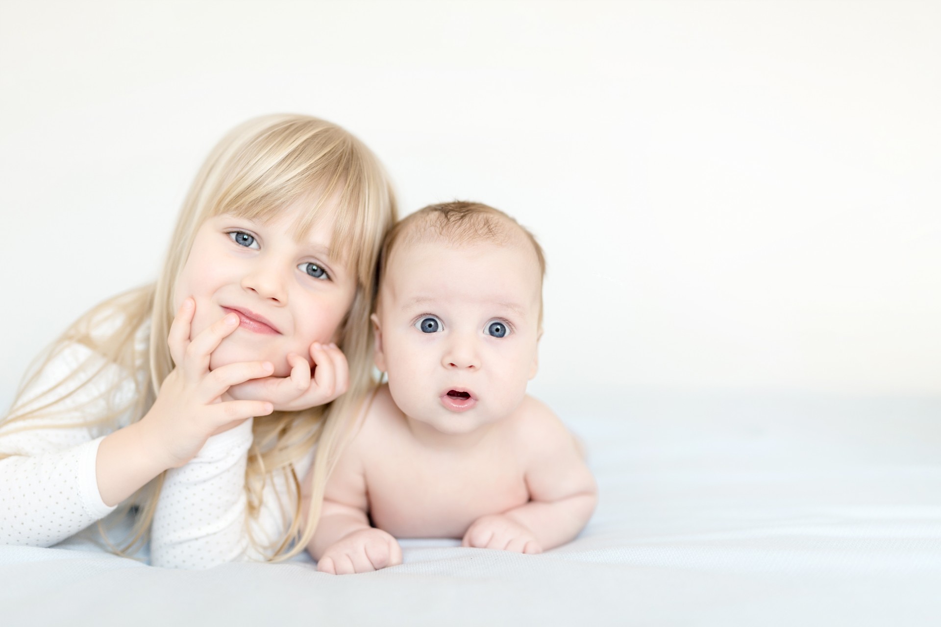 Portrait of brother and sister. Two cute children  lying on bed.  Open-eyed surprised or astonished expression. Brother and sister best friends, happy family and  childhood concept. 