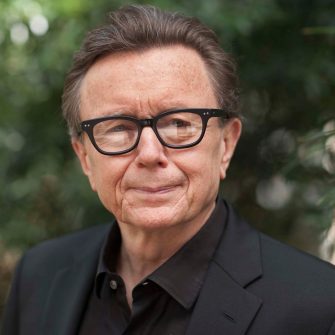 A man with black glasses in a black suit.