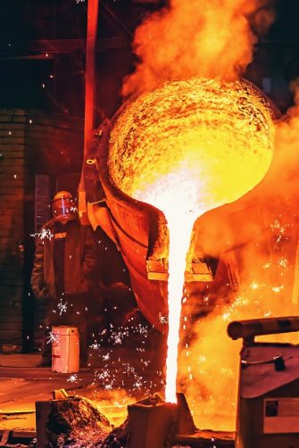 Liquid iron molten metal pouring in container, industrial metallurgical factory, foundry cast, heavy industry background.