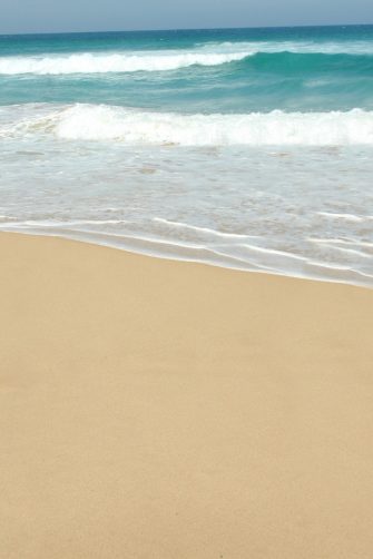 Dangerous current sign for swimmers at the beach in Australia. Lonely surfer entering the water on the background