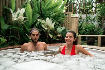 Man and woman take an ice bath outdoors in a tropical setting. Cold plunge for health, recovery, and resilience. A trending wellness practice combining nature, biohacking, and therapy
