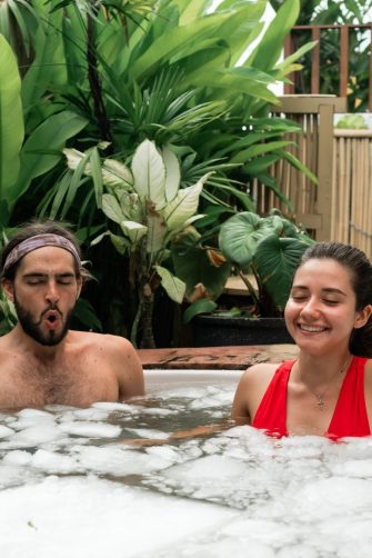 Man and woman take an ice bath outdoors in a tropical setting. Cold plunge for health, recovery, and resilience. A trending wellness practice combining nature, biohacking, and therapy