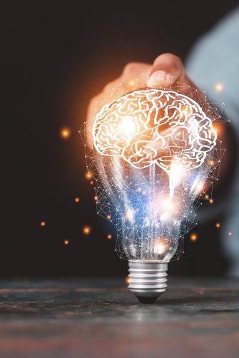 A person holding a lightbulb projecting a graphic of a brain
