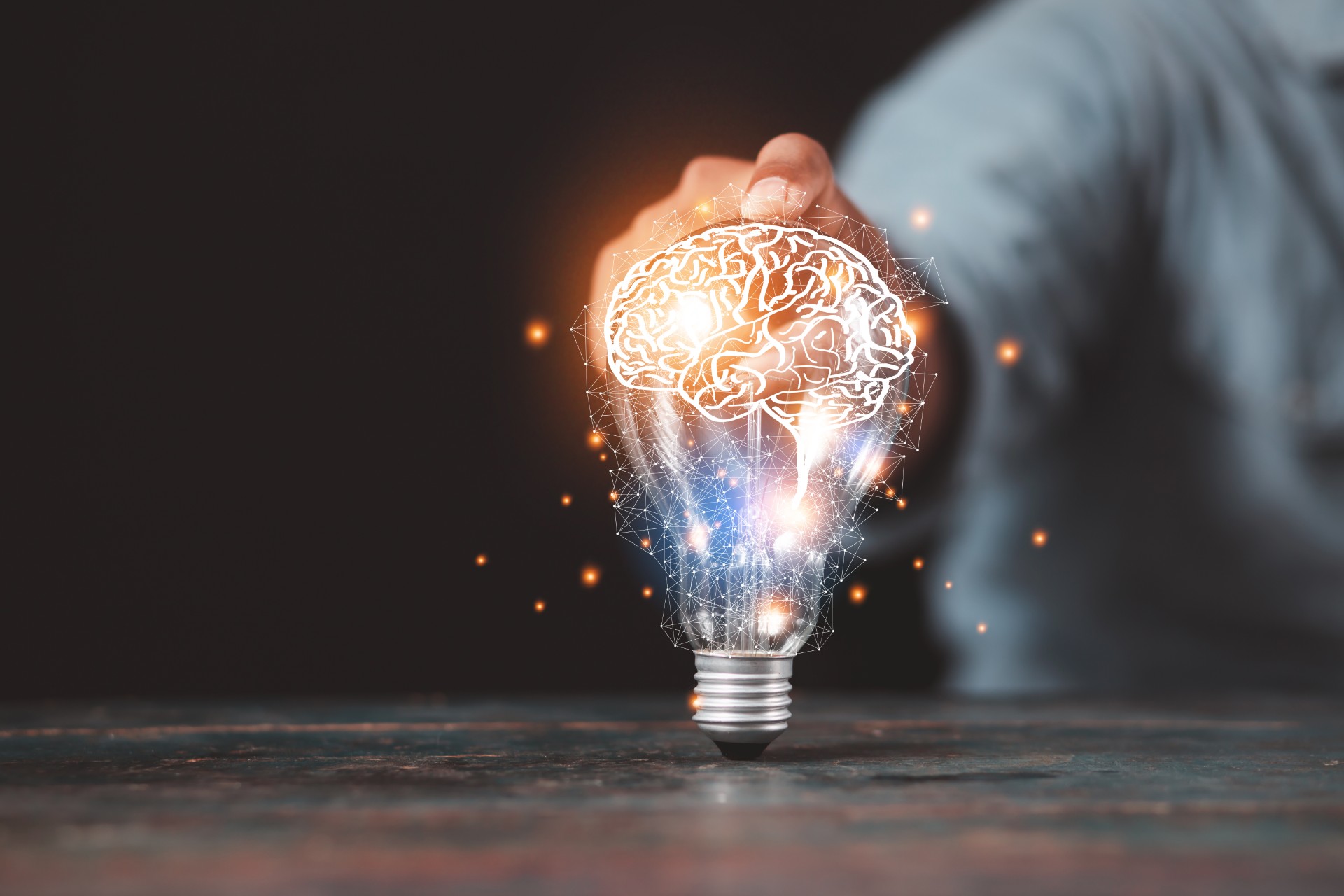 A person holding a lightbulb projecting a graphic of a brain
