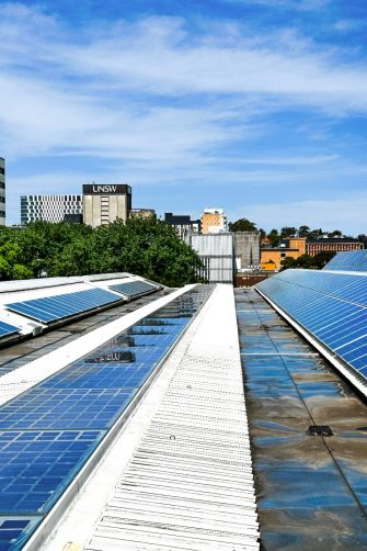 Rooftop solar panels in the foreground with UNSW Library in the background against blue sky