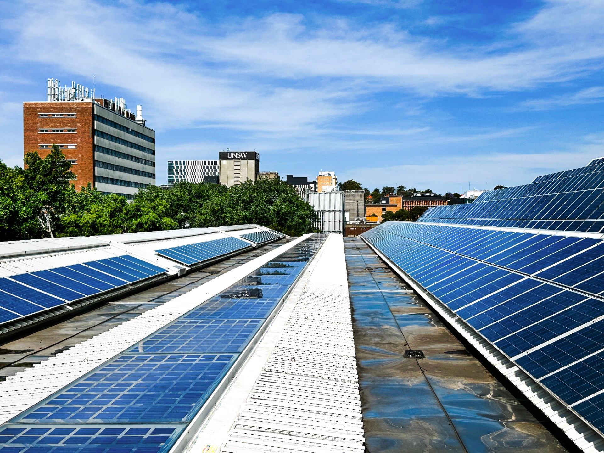 Rooftop solar panels in the foreground with UNSW Library in the background against blue sky