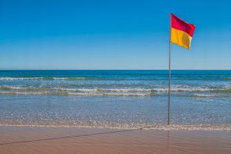 Beachscape with red and yellow flag indicating safe, patrolled beach in Australia