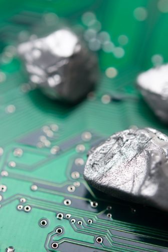 Mineral rare earth element on green electronic circuit board background copy space. US vs China chip war, tech war, semiconductor industry concept. China curbs on exports of rare earth element to US.