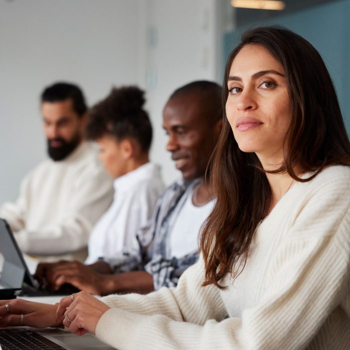 Smiling woman sitting during business meeting and looking at camera