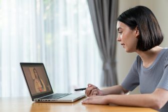 Asian young woman video call with doctor in living room at home. Patient girl consulting with general practitioner application computer laptop. Doctor and Consultant online and telemedicine concept.