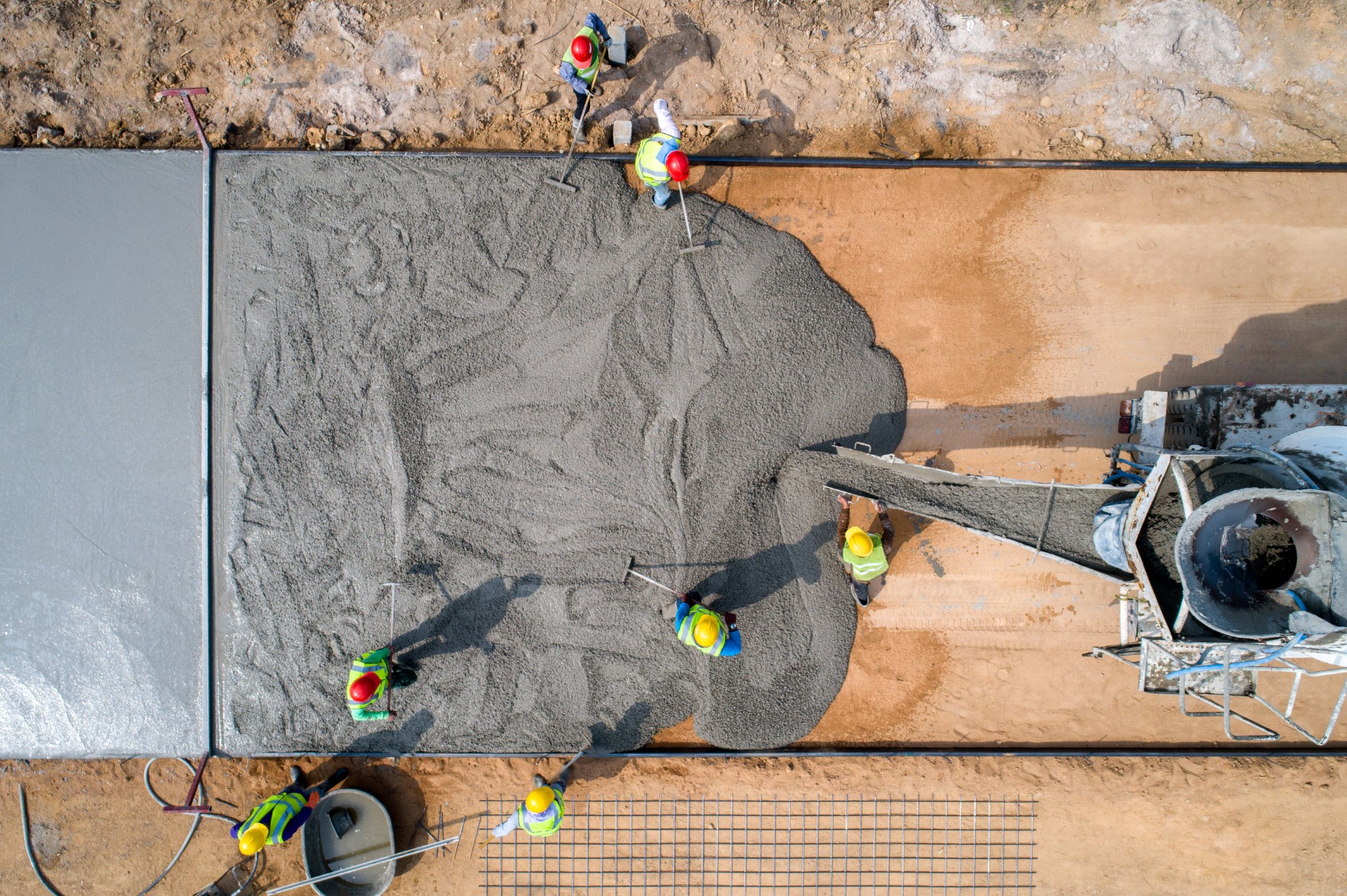 A construction worker pouring a wet concret at road construction site